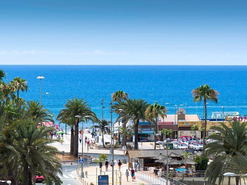 Pobřežní promenáda s palmami, obchody a výhledem na modré Středozemní moře