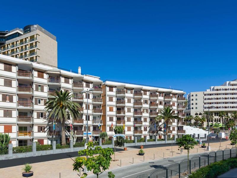 Vícepodlažní budovy s balkony pod jasnou modrou oblohou za slunečného dne.