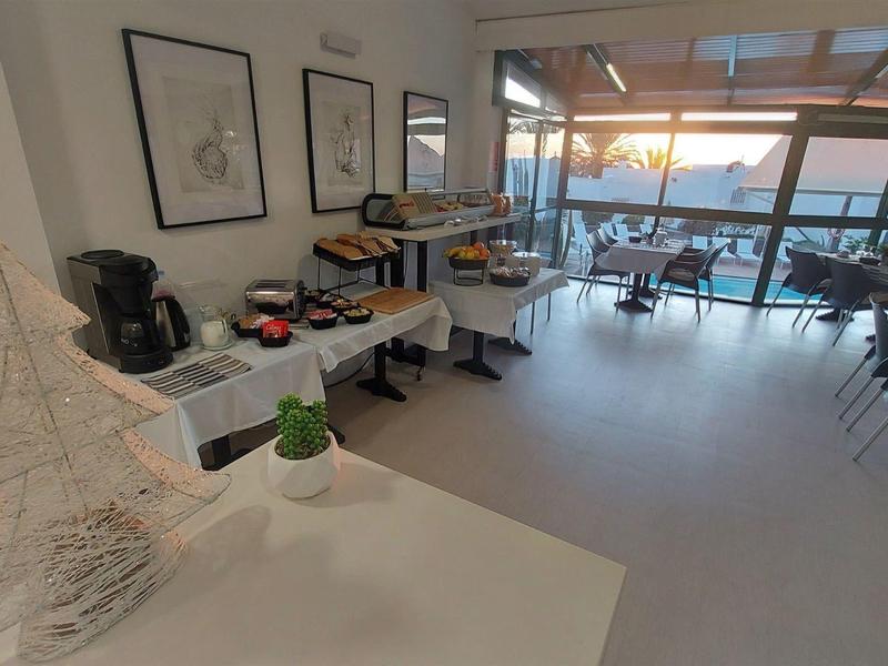 Modern hotel restaurant with large windows and water view at sunset.