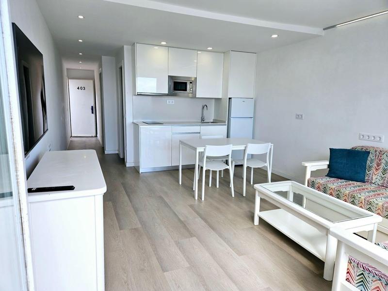 Modern open-plan living and kitchen area with dining table and sofa in neutral tones.