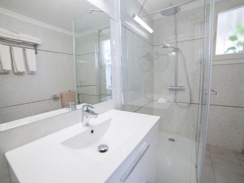 Modern bathroom with sink, mirror, towels, and shower with glass partition.