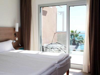 Modernes Hotelzimmer mit Doppelbett und Balkon mit Meerblick.