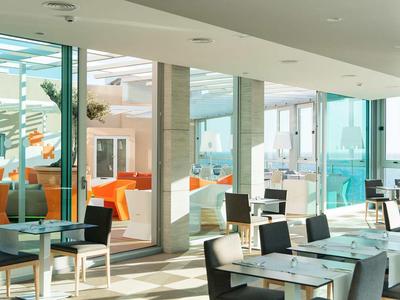 Helles Restaurant mit modernen Möbeln und Panoramafenstern mit Meerblick.