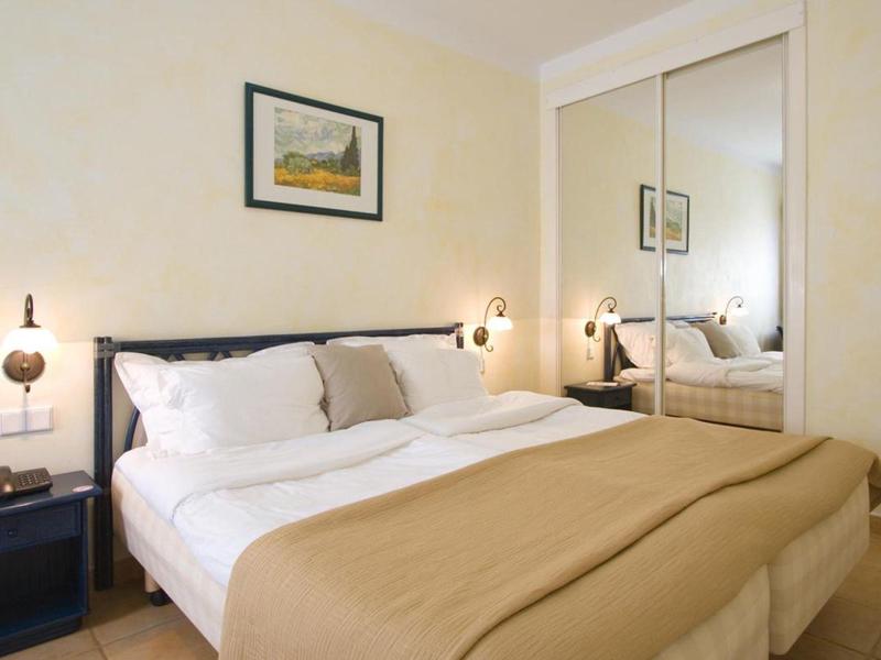 Helles Schlafzimmer mit großem Bett, brauner Decke, Nachttischen und Spiegel-Schrank.