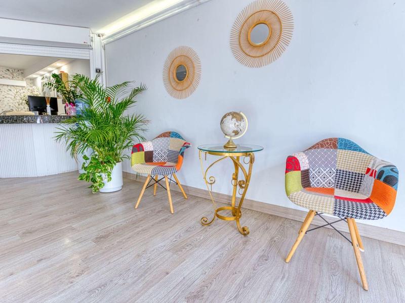 Espace d'attente lumineux avec des fauteuils colorés, une petite table et une plante verte.