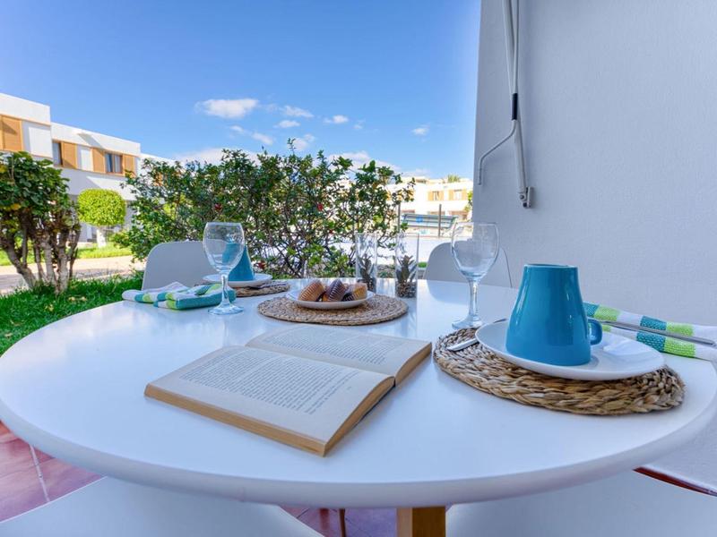 Table blanche avec livre ouvert, vaisselle et vue sur jardin et bâtiments de l'hôtel par temps ensoleillé