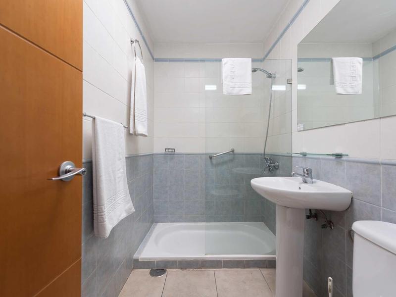 Kleines modernes Badezimmer mit Dusche, Waschbecken, Toilette und weißen Handtüchern an der Wand.