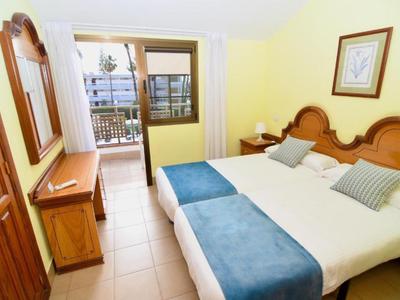 Hotel room with two twin beds, blue blankets, and a balcony with a view.