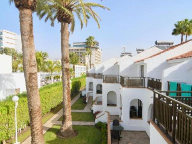 Resort with tall palm trees and white buildings under a clear blue sky.