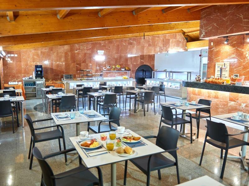 Restaurant mit Holzbalken, rot-braunen Wänden, mehreren Tischen und Stühlen, gedeckt mit Geschirr und Speisen.