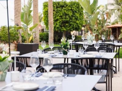 Elegantes Freiluftrestaurant mit gedeckten Tischen und Weinserviergläsern im Garten.