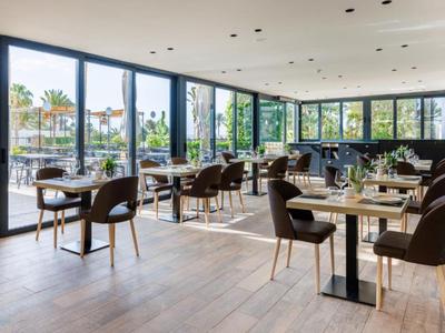 Modernes Restaurant mit großen Fenstern und stilvollen Holzmöbeln, hell und luftig.