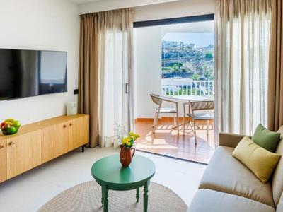 Helles Wohnzimmer mit Balkon, bequemer Couch, grünem Tisch und Stadtblick.