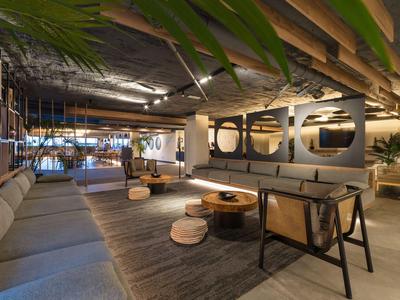 Modern eingerichteter Hotel-Loungesalon mit Sofas, Holztischen und Pflanzen.