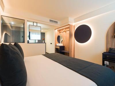 Modernes Hotelzimmer mit großem Bett, schwarzer Bettdecke und minimalistischer Einrichtung.