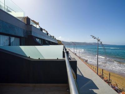 Balcone moderno dell'hotel con ringhiera in vetro, vista mare e accesso alla spiaggia.