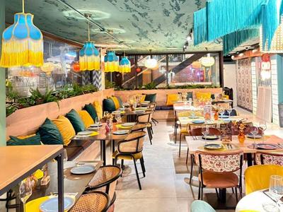 Modernes Restaurant mit bunten Lampen und gemütlichen Sitzbereichen in warmen Farben.