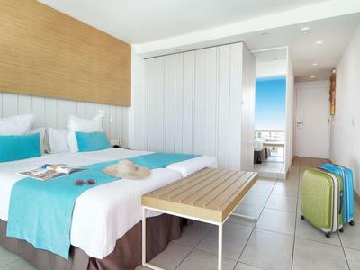 Habitación de hotel moderna con cama doble, acentos turquesa y maletas.