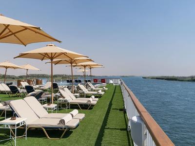 Sdraio sotto ombrelloni lungo un pontile sul fiume con cielo azzurro limpido