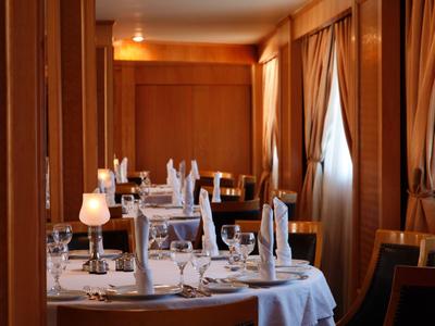 Ristorante elegante con tavoli apparecchiati e luce calda che filtra attraverso le tende.