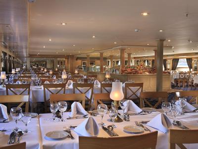 Ristorante elegante e spazioso con tavoli apparecchiati e illuminazione calda.