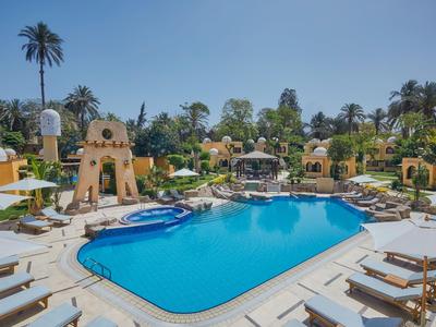 Großer Pool mit Liegestühlen und tropischer Gartenanlage in einem Hotelresort.