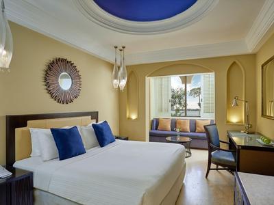 Modern eingerichtetes Hotelzimmer mit Doppelbett, blauem Kuppeldeckenfenster und Sitzbereich am Fenster