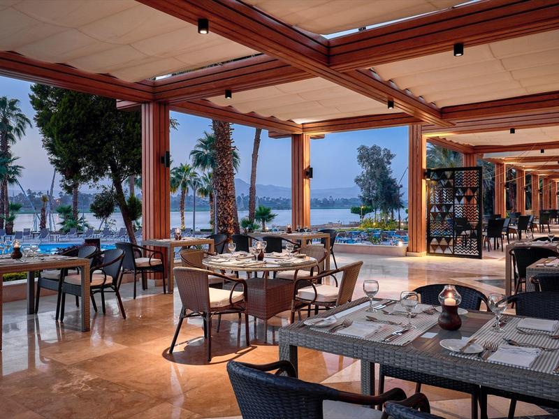 Elegantní venkovní restaurace s výhledem na moře, teplé dekorace a prostřené stoly.