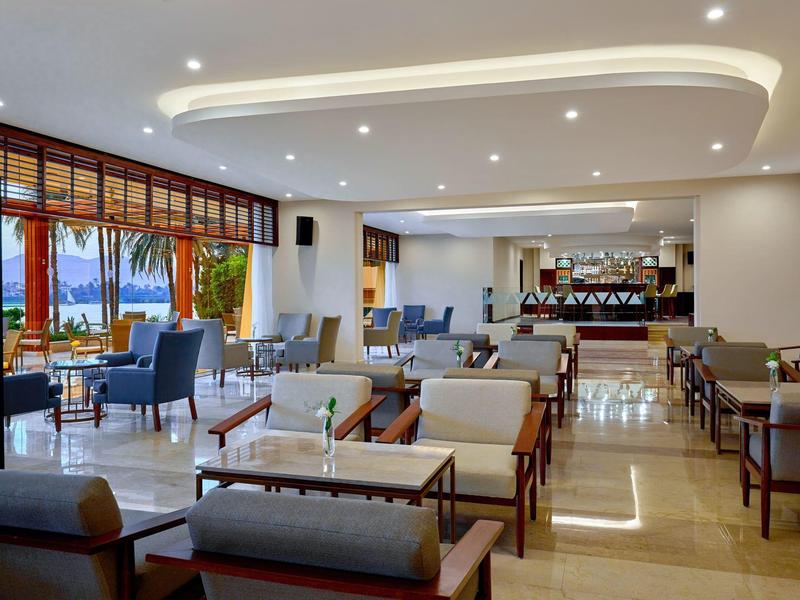 Moderní hotelový salonek se světlým dřevěným nábytkem a velkými okny, světlý a prostorný prostor.