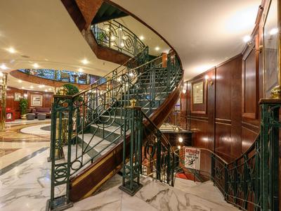 Eleganckie spiralne schody z zieloną balustradą w luksusowym holu hotelowym.
