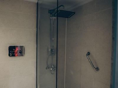 Moderne Dusche mit Glaswand, Rainfall-Duschkopf, Handbrause und weißem WC in schlichtem Badezimmer.