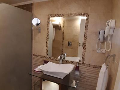 Modernes Badezimmer mit eckigem Waschbecken, großem Spiegel und grauer Duschabtrennung.