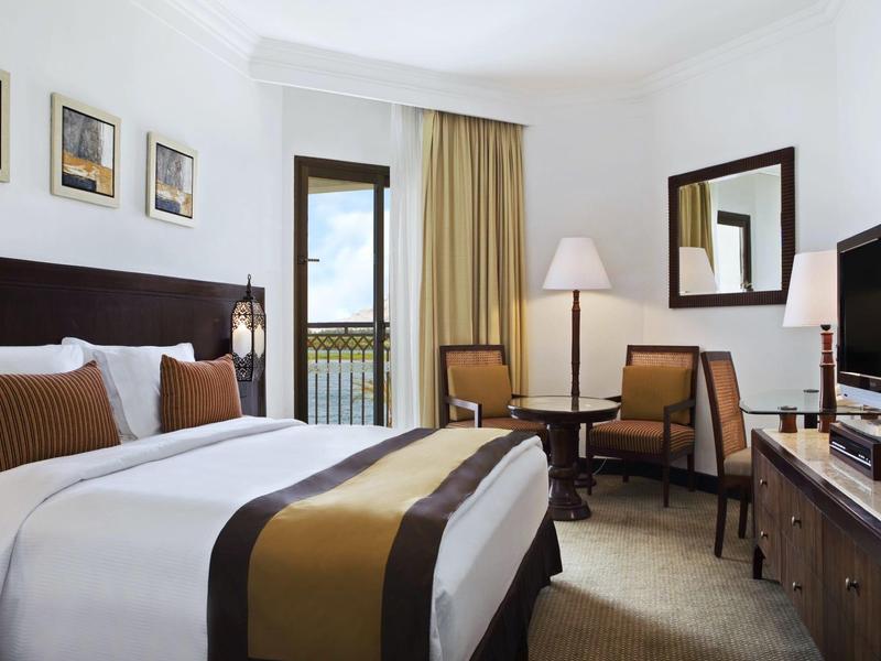 Modernes Hotelzimmer mit Doppelbett, Schreibtisch, Stühlen und Fernseher.