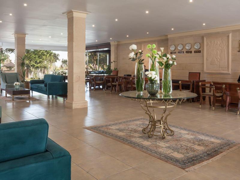 Elegant hotel lobby area with columns, central table decoration, and comfortable seating.