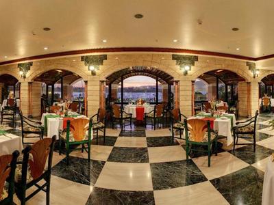 Elegantes Restaurant mit schwarz-weiß kariertem Boden, dekorierten Tischen und warmem Licht.