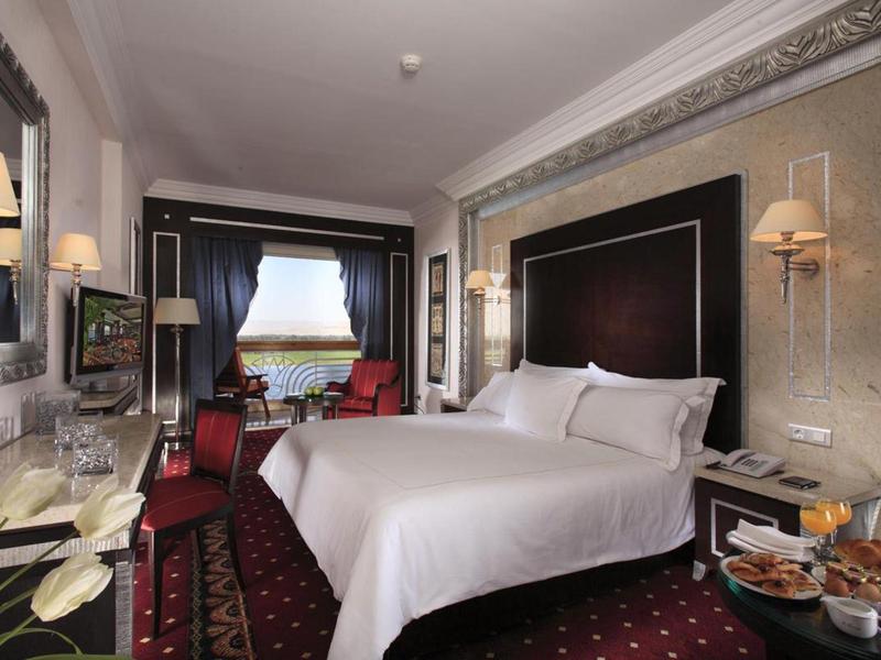 Habitación de hotel cómoda con cama grande, área de descanso y decoración elegante.