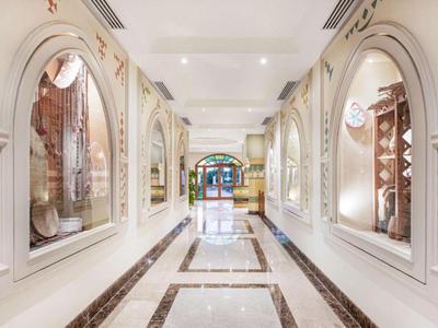 Un corridoio d'hotel luminoso e decorativo con finestre ad arco e motivi tradizionali sulle pareti.