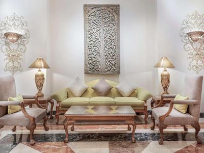 Soggiorno elegante con divano, poltrone, lampade e ornamenti decorativi a parete.