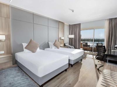 Camera d'hotel moderna con due letti singoli, scrivania e balcone con vista.