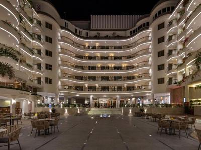 Cortile di un hotel illuminato con piscina e tavoli di notte