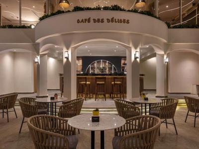 Caffè elegante con tavoli rotondi e sedie di vimini in ambiente interno illuminato soffusamente.