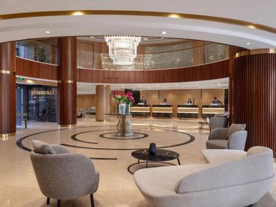 Atrio dell'hotel con aree salotto accoglienti, tappeto rotondo e illuminazione moderna.