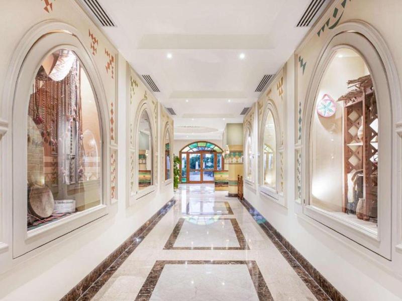 Corridoio luminoso con archi di finestre decorati e motivi decorativi sulle pareti.