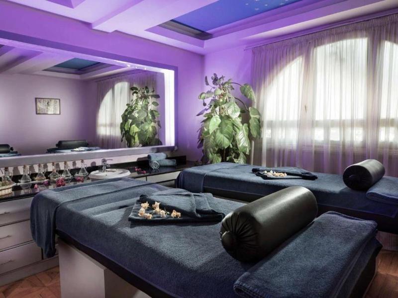 Elegante stanza spa con due lettini per trattamenti e illuminazione viola soffusa.