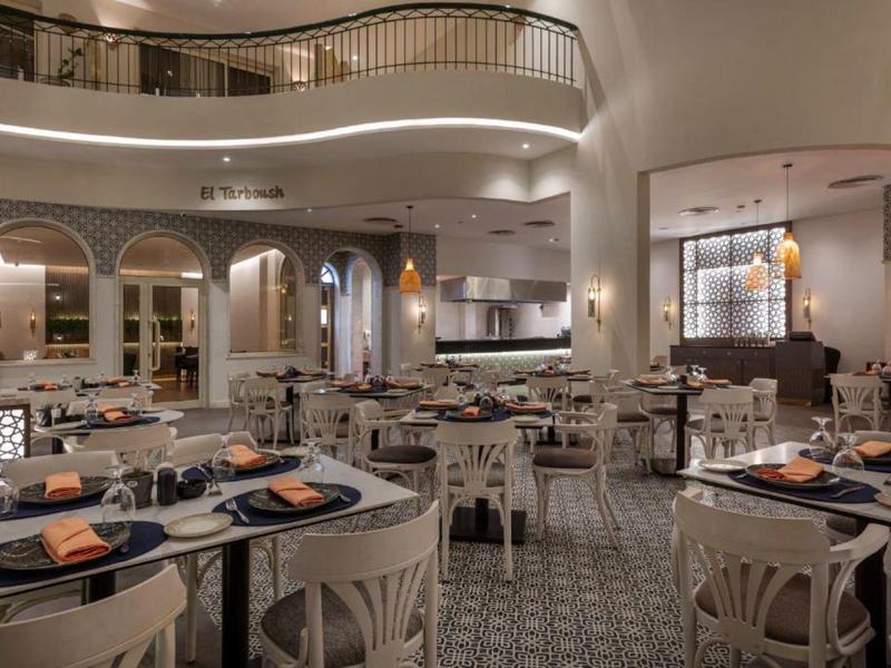 Ristorante elegante e moderno con sedie bianche e tavoli apparecchiati con stile sotto una luce calda.