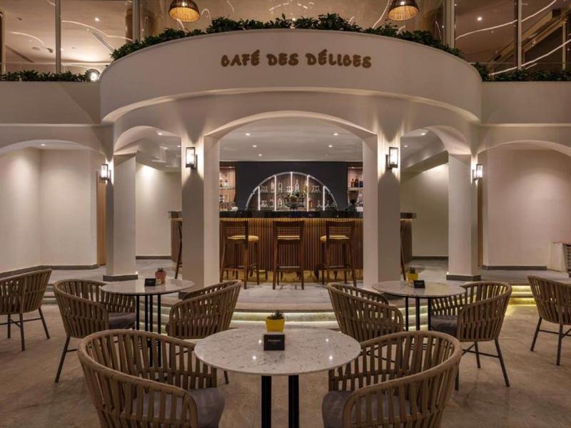 Caffè elegante con tavoli rotondi e sedie di vimini in ambiente interno illuminato soffusamente.