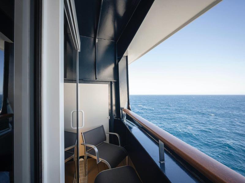 Balkon mit zwei Stühlen und Blick auf das Meer an einem sonnigen Tag.