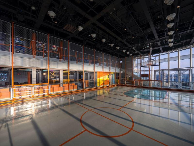 Helle, moderne Sporthalle mit großem Fenster und Basketballmarkierungen auf dem Boden.