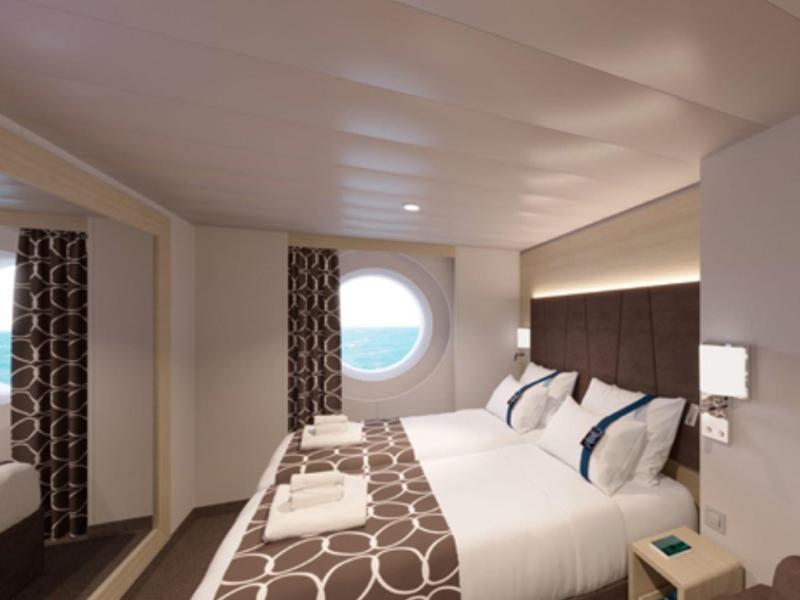 Helles Hotelzimmer mit rundem Fenster, Doppelbett und modernen braunen Vorhängen.