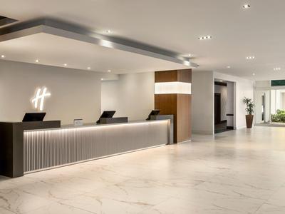 Moderne Hotellobby mit langem Empfangstresen, heller Marmoroptik und zurückhaltender Beleuchtung.